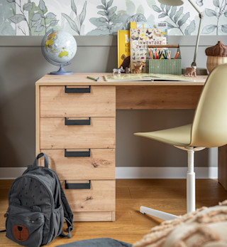 Drewniane biurko dziecięce z szufladami, przy którym stoją książki, globus i przybory szkolne, tworząc przyjazny kącik do nauki.
