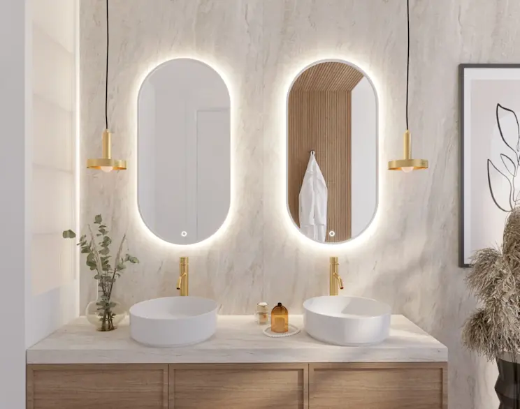 Nowoczesna łazienka z dwoma owalnymi lustrami Arducati z podświetleniem LED nad podwójną umywalką. W aranżacji widać złotą armaturę, drewnianą szafkę i jasny blat, a delikatne lampy wiszące podkreślają elegancki klimat wnętrza.