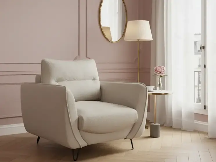 Jasnobeżowy fotel Silva Manhattan 18 ustawiony w eleganckim salonie z różową ścianą, lustrem, lampą podłogową i stolikiem pomocniczym.
