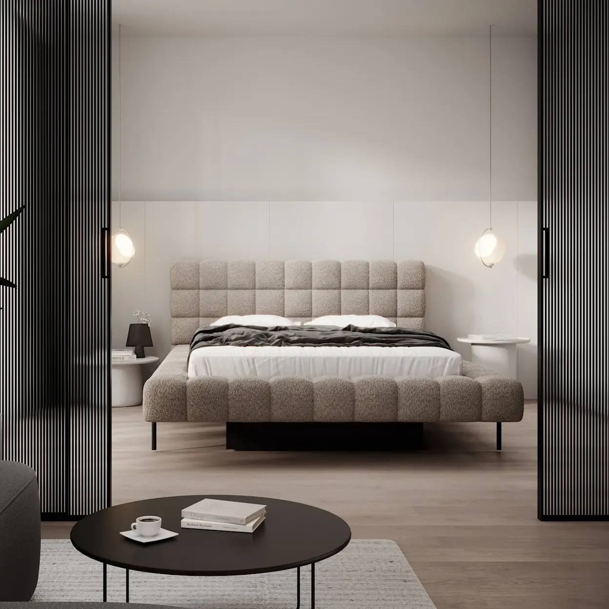 Tapicerowane łóżko Magentta w jasnobeżowej tkaninie z pikowanym zagłówkiem stoi w minimalistycznej sypialni. Po bokach wiszą kuliste lampy, a wnętrze podkreślają czarne lamele przy wejściu.