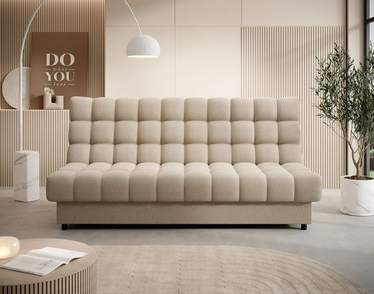 Jasnobeżowa wersalka Clareta z miękką, pikowaną tapicerką stoi w nowoczesnym salonie. W tle ściana z lamelami, łukowa lampa oraz duża roślina w jasnej donicy.