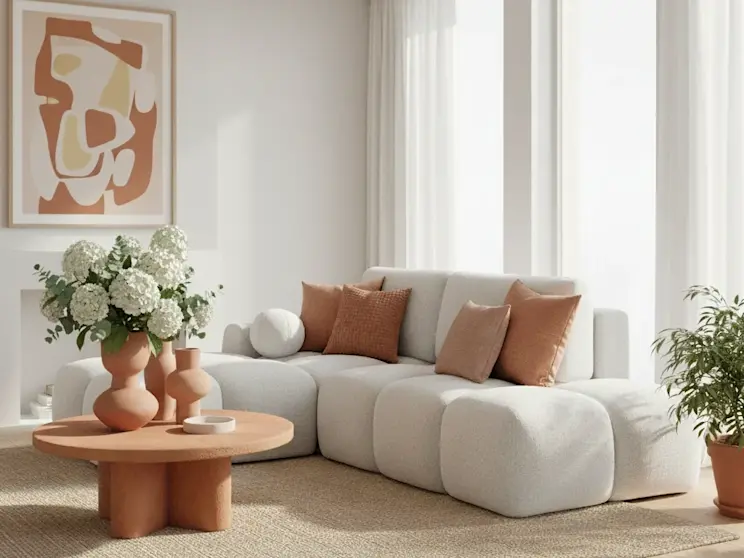 Lewostronny narożnik Vittario w tkaninie Royal 01 w mlecznej bieli, zaprezentowany w jasnym salonie z naturalnymi dodatkami w kolorze ciepłej terracotty