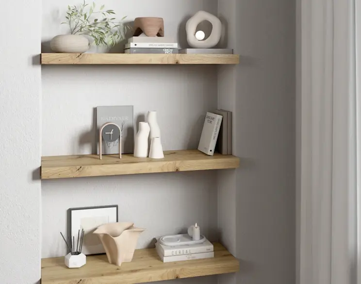 Drewniane półki Garris z dekoracjami w jasnym, minimalistycznym wnętrzu, ozdobione książkami, wazonami i rośliną w stonowanej kolorystyce.