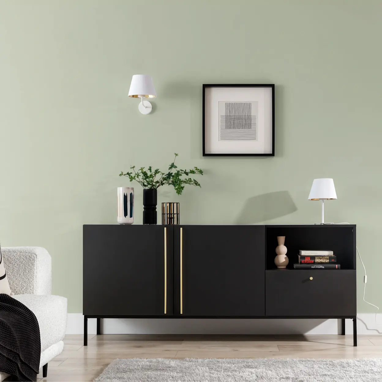 Nowoczesny salon z czarną komodą Lanzzi na metalowych nogach, kinkietem Vespillo i lampką nocną Vespill na tle zielonej ściany.