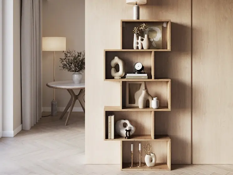 Regał Sottis o geometrycznej formie, idealny do salonu lub przedpokoju, z miejscem na książki, świece i dekoracje. Jasne wnętrze w ciepłej palecie barw podkreśla elegancki styl i porządek w przestrzeni.