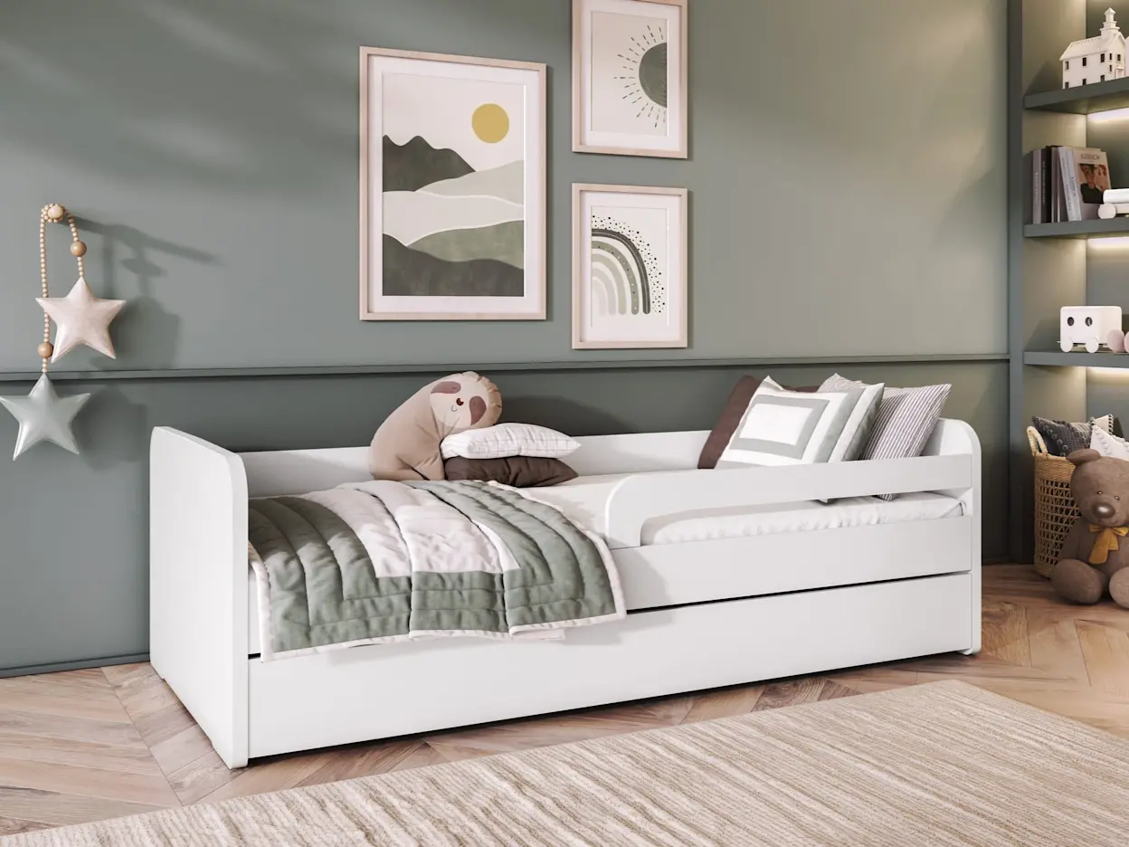 Nowoczesne łóżko dla dziecka Duuli z materacem, białe i minimalistyczne, ustawione na drewnianej podłodze. Zabezpieczające boki, miękka narzuta i poduszki sprawiają, że to komfortowe rozwiązanie na co dzień.