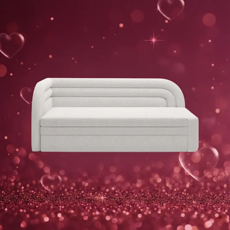 Jasna sofa Fabillo w tkaninie boucle na walentynkowym tle. Miękka struktura materiału i nowoczesna forma sprawiają, że sofa wygląda elegancko i przytulnie. Idealna sofa do salonu dla osób ceniących komfort.