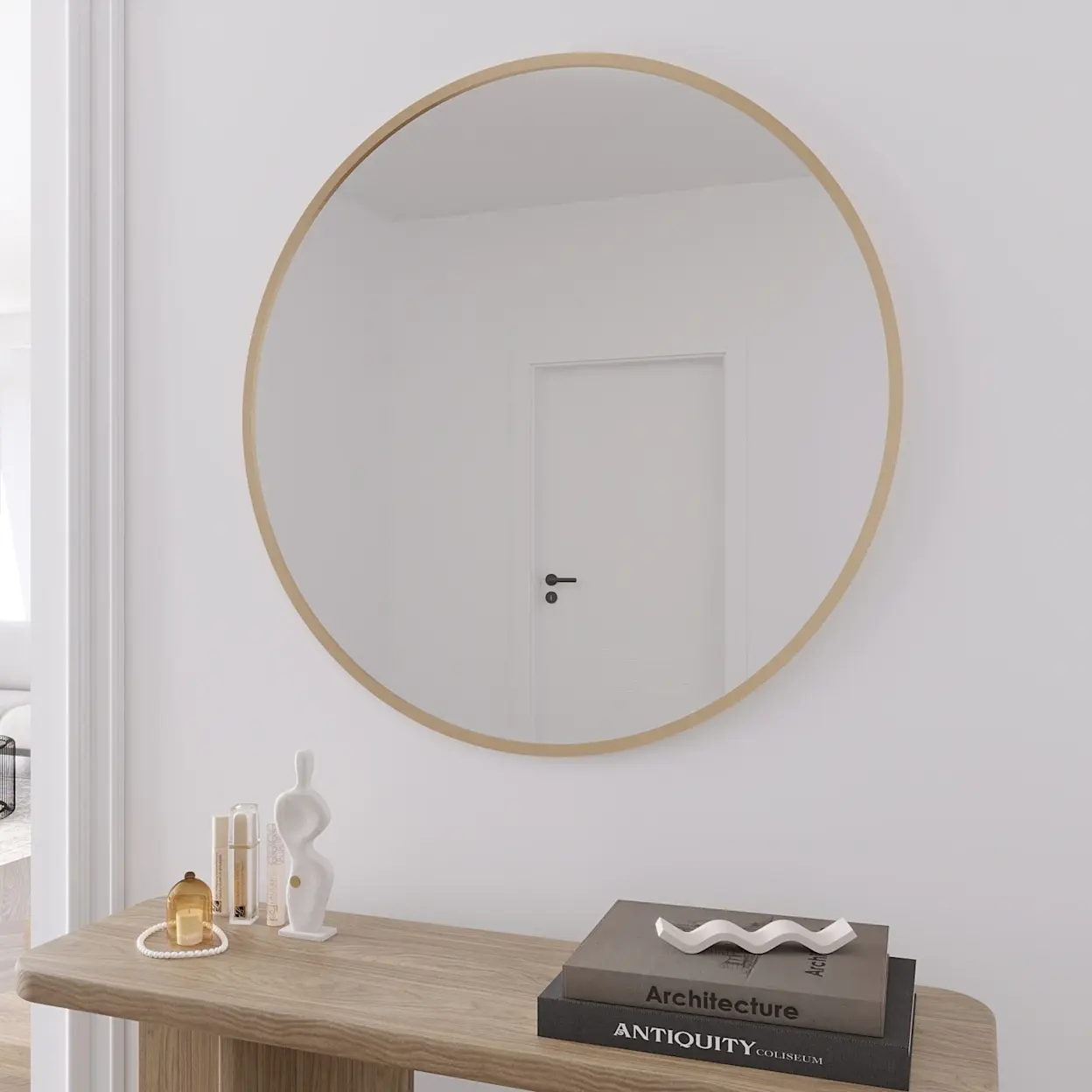 Okrągłe lustro Gerbinie w złotej ramie zawieszone na jasnej ścianie nad drewnianą konsolą. Minimalistyczna aranżacja z dekoracjami i książkami tworzy elegancki przedpokój w stylu nowoczesnym.