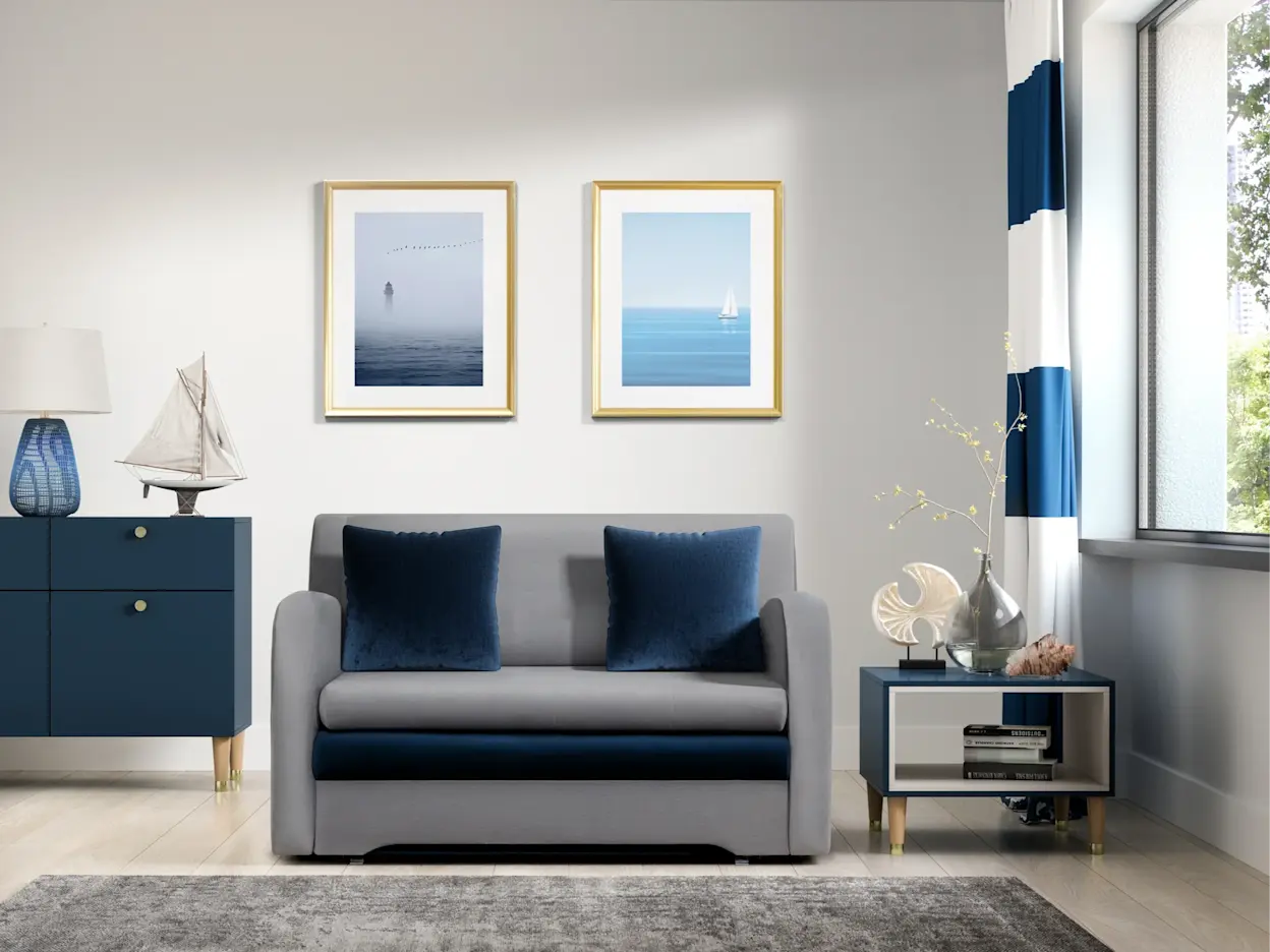 Szara kanapa Ario z granatowymi poduszkami zestawiona z dywanem Codrila w jasnym salonie w nadmorskim stylu, z dekoracjami w odcieniach granatu.