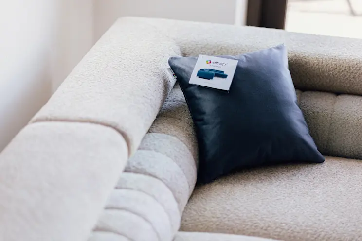 Granatowa poszewka dekoracyjna Monolith 77 ułożona na jasnej, miękkiej sofie o wyraźnej fakturze. Zbliżenie pokazuje elegancki kontrast kolorów i przytulny charakter strefy wypoczynku w salonie.