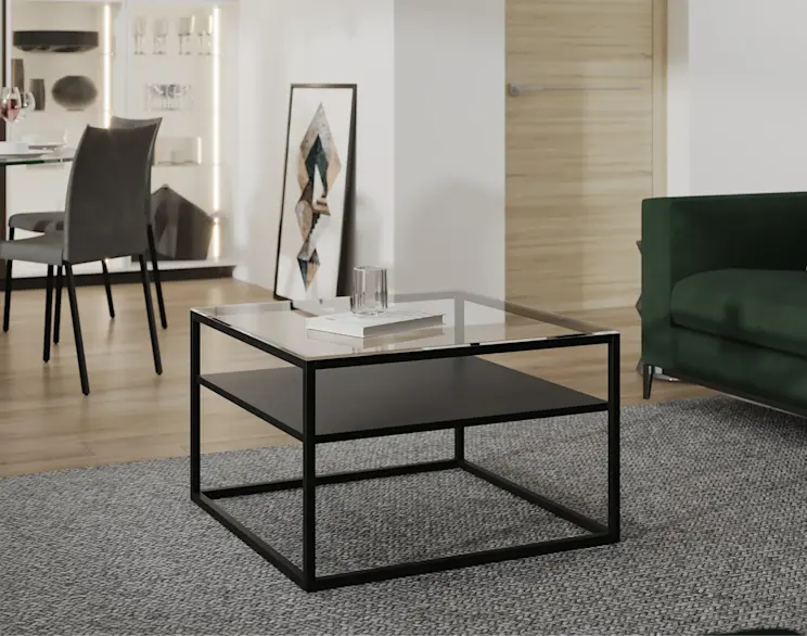 Nowoczesny stolik kawowy Linze z metalową ramą i szklanym blatem, ustawiony w eleganckim salonie z zieloną sofą i jasnym wykończeniem wnętrza.