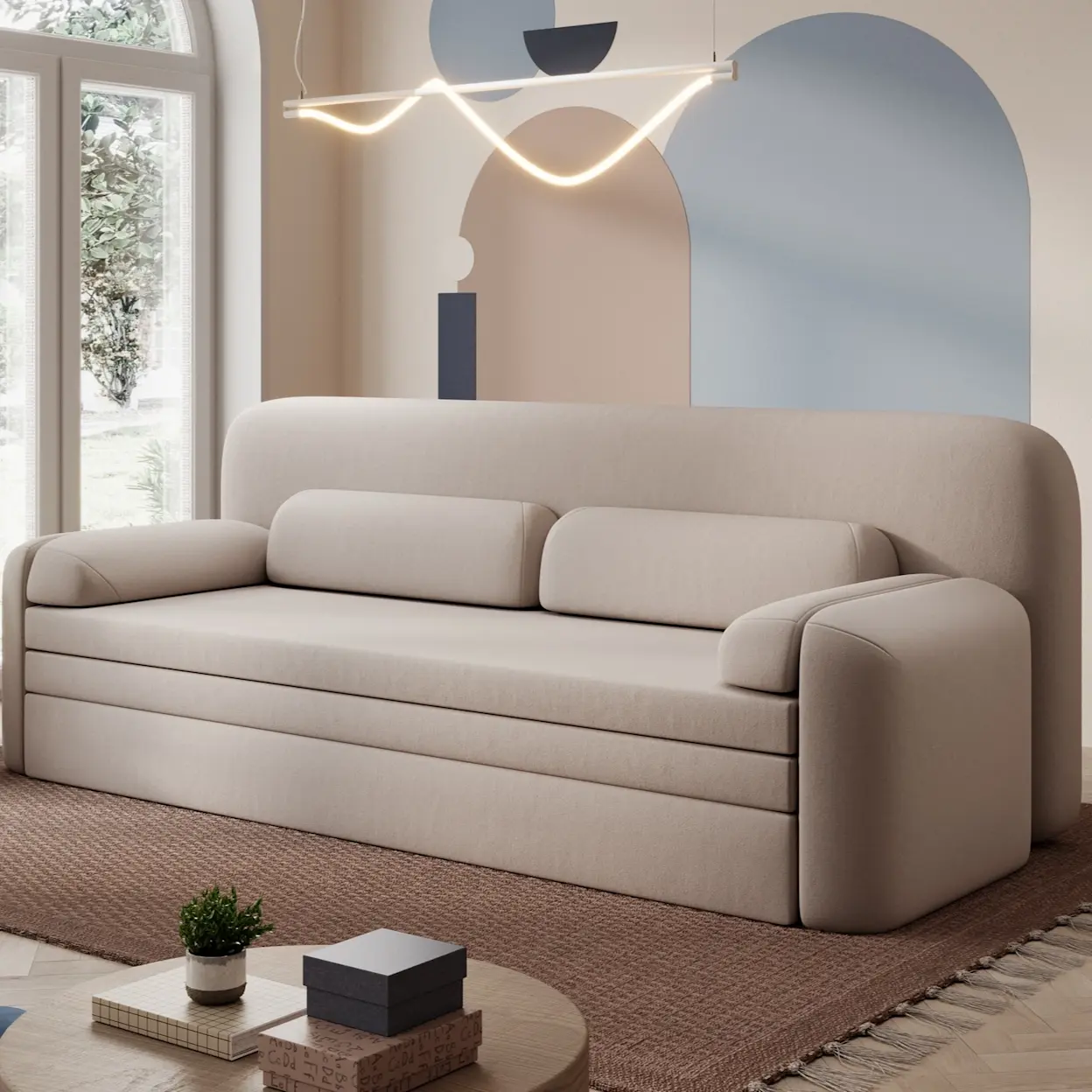 Beżowa kanapa Elioss Sola 18 w nowoczesnym salonie, z zaokrąglonymi bokami i miękkimi poduchami. Jasna aranżacja z designerską lampą i pastelową ścianą podkreśla lekkość wnętrza.