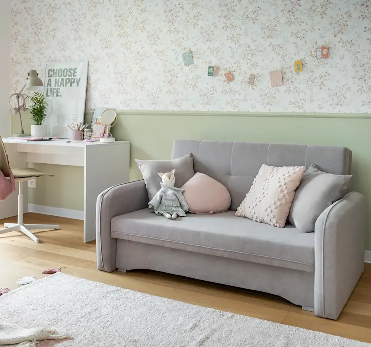 Kanapa Laine i biurko Nevy w jasnym, pastelowym pokoju dziecięcym z dekoracjami, miękkimi poduszkami i przytulnym charakterem sprzyjającym nauce i zabawie.