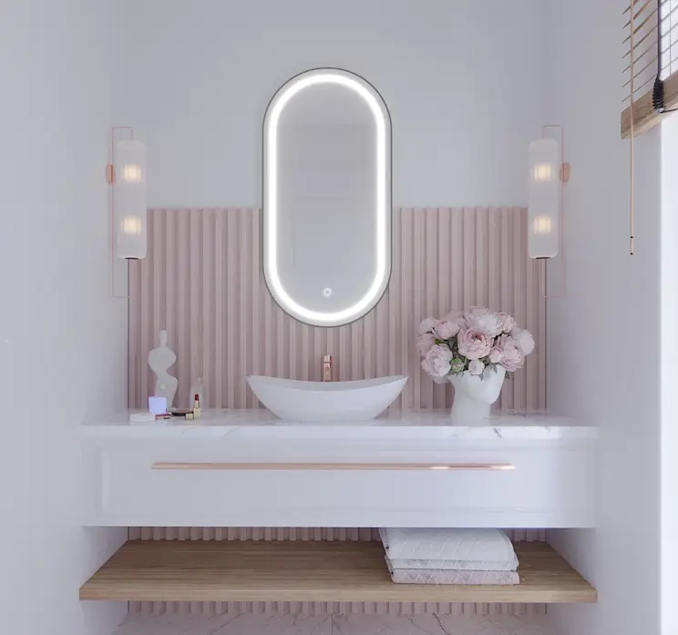 Owalne lustro Robienti z podświetleniem LED, zawieszone nad umywalką w eleganckiej łazience z różowymi lamelami i kobiecymi dodatkami.