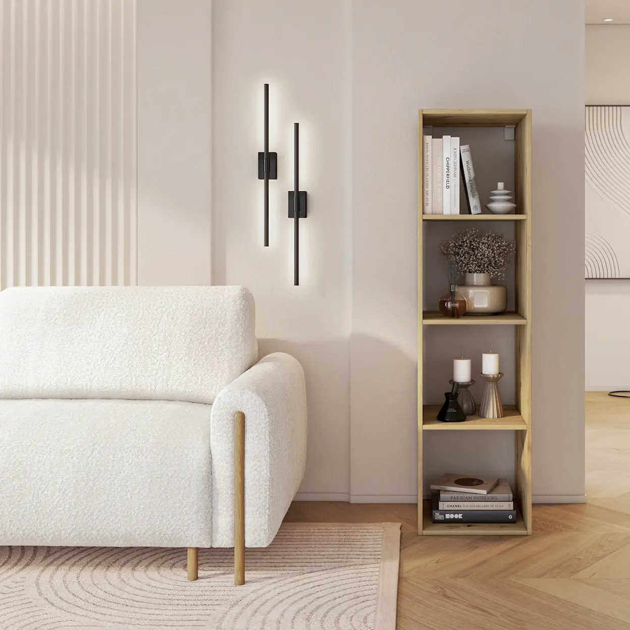 Jasny salon w stylu skandynawskim z kanapą Arcadova i wąskim regałem Figgi na książki oraz dekoracje, na tle neutralnej ściany.