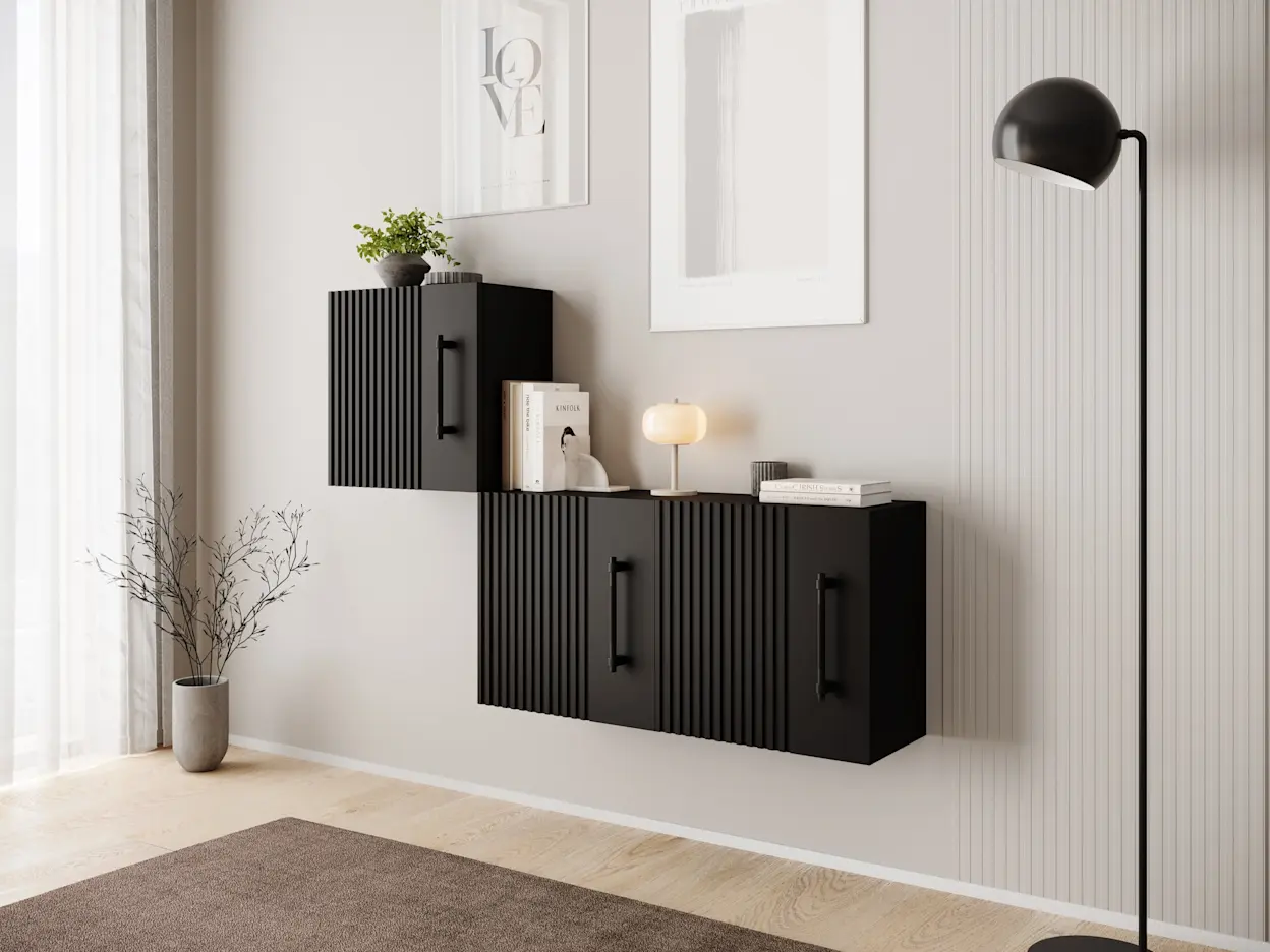 Trzy czarne szafki Raftt z ryflowanymi frontami zawieszone na ścianie w salonie, z dodatkami w stylu minimalistycznym i nowoczesną lampą.