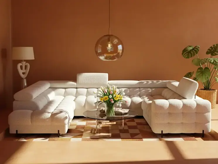 Jasny narożnik Fectory Royal 01 z pikowanym siedziskiem ustawiony w eleganckim salonie z terakotową ścianą, stolikiem kawowym i dekoracyjnymi kwiatami.