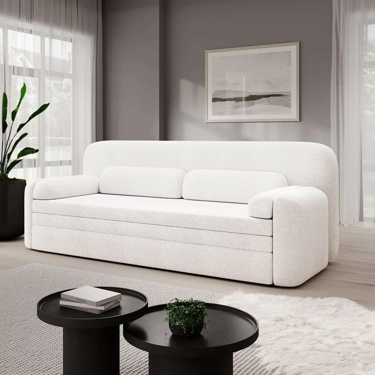 Biała kanapa Elioss Royal 01 w tkaninie boucle w jasnym salonie. Sofa ma zaokrąglone boki i miękkie poduszki oparciowe. Przed nią stoją dwa czarne, okrągłe stoliki kawowe z dekoracją, a na podłodze leży jasny dywan oraz futrzasta narzuta.