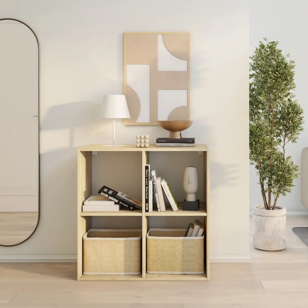 Drewniany regał Jugis w jasnym odcieniu, ustawiony przy ścianie w skandynawskim wnętrzu. Na półkach książki i dekoracje, na dole dwa kosze, a na blacie stoi lampka i dodatki w naturalnych barwach.