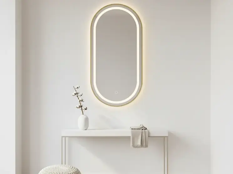 Nowoczesne lustro Micedi L o owalnym kształcie z delikatnym podświetleniem LED, zawieszone nad minimalistyczną konsolą w jasnym wnętrzu przedpokoju z naturalnymi dodatkami.