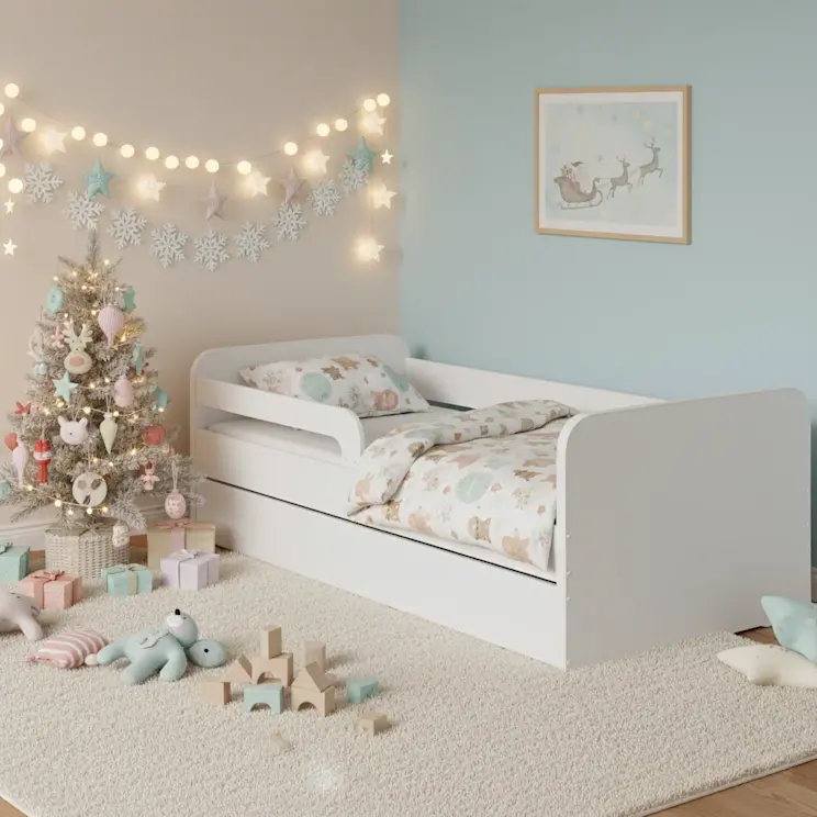 Białe łóżko Duuli w pastelowym pokoju dziecięcym z małą choinką, prezentami i świątecznymi dekoracjami, tworzące ciepły, magiczny klimat.