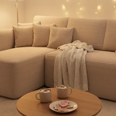 Beżowy narożnik Hadson w przytulnym salonie z ciepłym oświetleniem. Miękkie poduszki i strukturalna tapicerka tworzą komfortową strefę relaksu, idealną na rodzinne wieczory i odpoczynek.