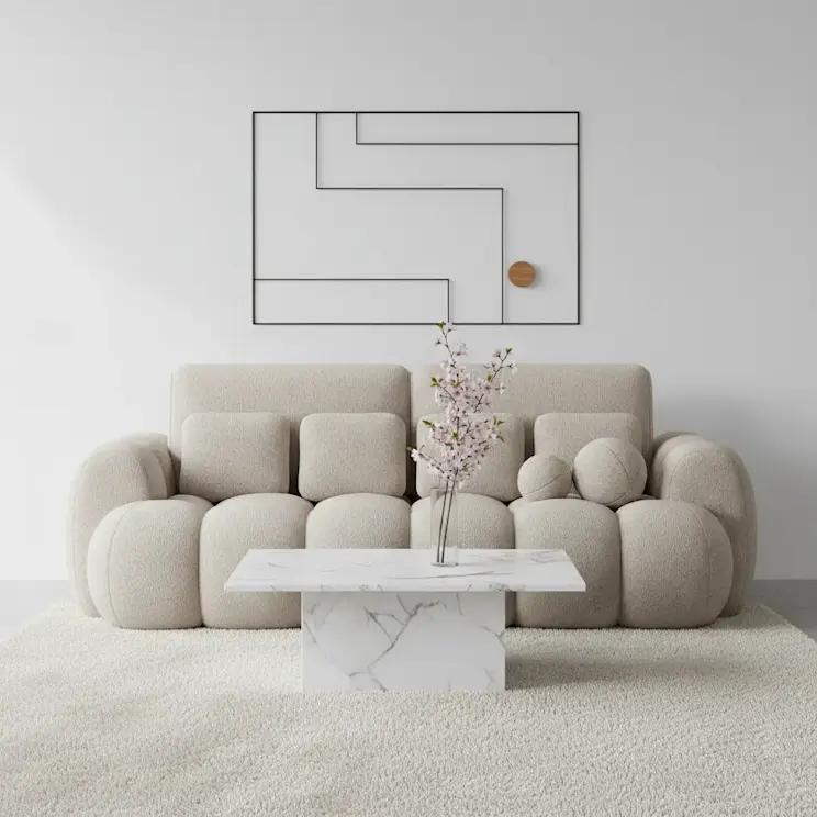 Beżowa sofa Cotonn w nowoczesnej aranżacji salonu z jasną ścianą i miękkim dywanem. Przed sofą ustawiono marmurowy stolik kawowy z wazonem z delikatnymi kwiatami, a na ścianie znajduje się minimalistyczna dekoracja.
