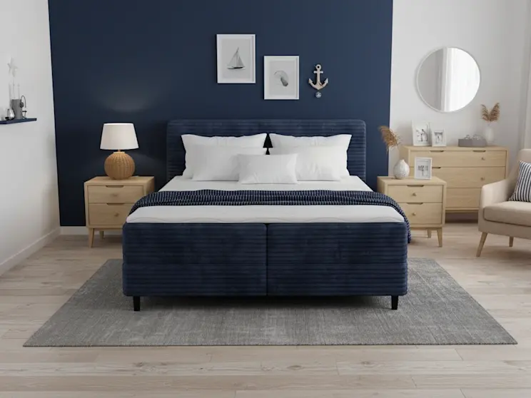 Stylowa aranżacja z łóżkiem Cortiko w odcieniu granatu, połączona z białymi ścianami i naturalnym drewnem.