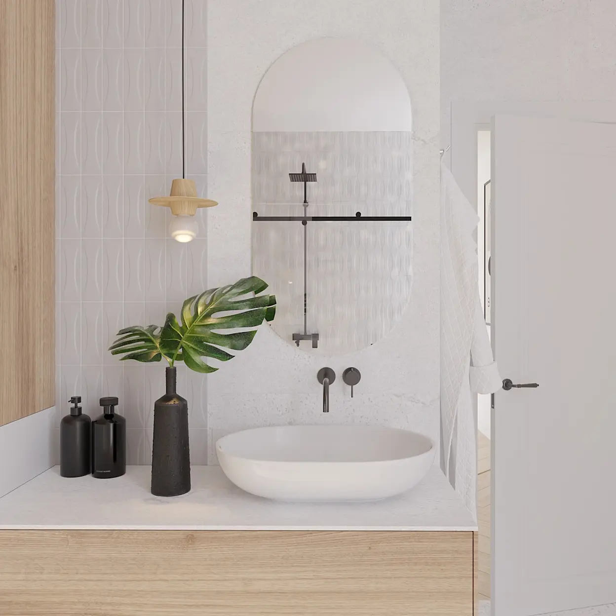 Owalne lustro Nunisse bez ramy zawieszone nad białą umywalką nablatową w jasnej łazience. W aranżacji widać drewnianą szafkę, czarną baterię podtynkową, dekoracyjną roślinę w wazonie i minimalistyczne dodatki.