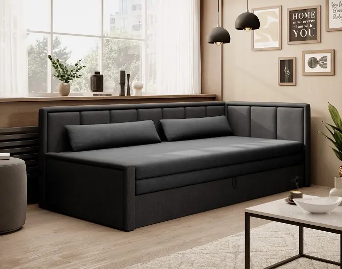 Kanapa rozkładana Fulgeo w tkaninach Poco 04 i Poco 10 w kolorze szarym i czarnym, ustawiona przy dużym oknie. Wnętrze ocieplają beżowe ściany, czarne lampy wiszące i galeria ramek, a z przodu widać stolik kawowy.