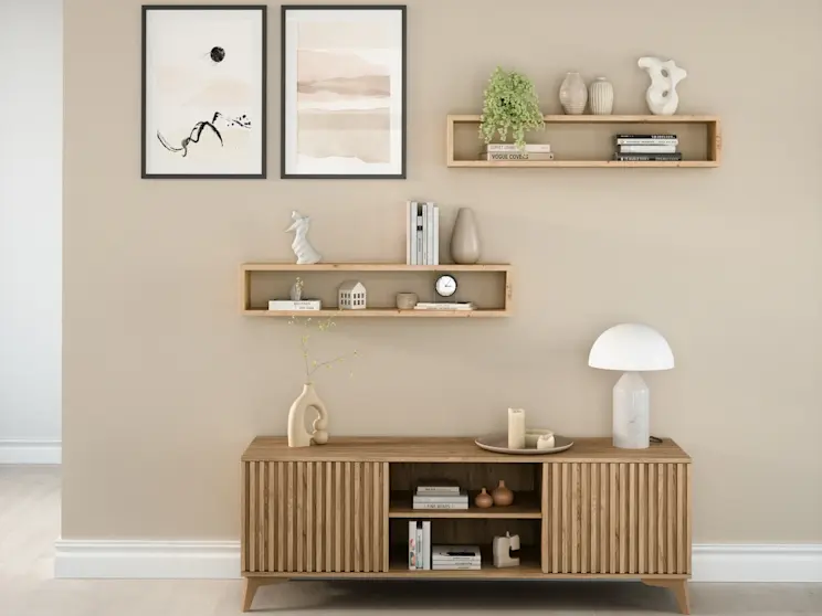 Nowoczesny salon z drewnianą szafką RTV Entsian i półkami Finees, uzupełniony delikatnymi dekoracjami w spokojnej, naturalnej kolorystyce.