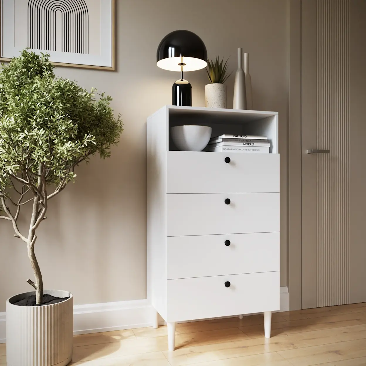 Biały regał Dullum z czterema szufladami i otwartą półką ustawiony przy jasnej ścianie w salonie. Na górze stoi czarna lampa, dekoracje i książki, a obok widoczna jest zielona roślina w donicy.
