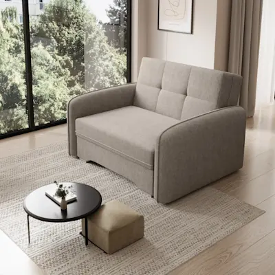 Szara kanapa Laine w tkaninie Poco 07 ustawiona w jasnym salonie przy dużym oknie. Mebel ma szerokie podłokietniki i proste przeszycia na oparciu, dzięki czemu wygląda nowocześnie i pasuje do minimalistycznych wnętrz.