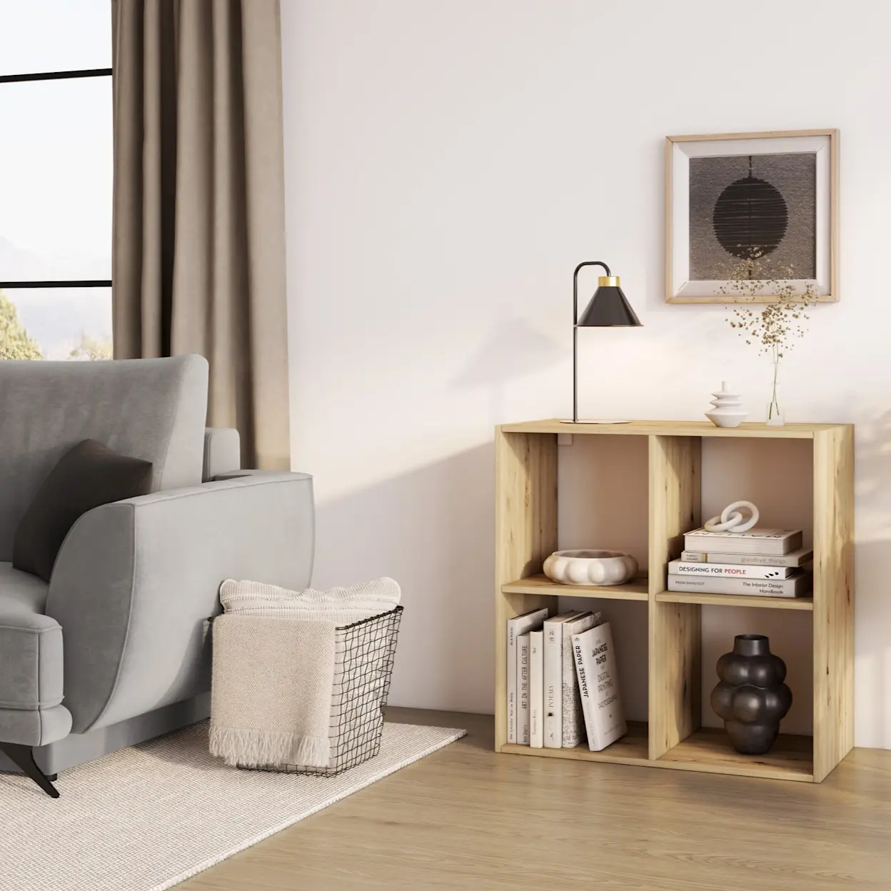 Minimalistyczny salon z jasną kanapą Megis w tkaninie Monolith 84, obok drewniany regał Jugis z książkami i dekoracjami. Na blacie stoi lampka Detme, a całość dopełniają zasłony i spokojne, ciepłe światło.