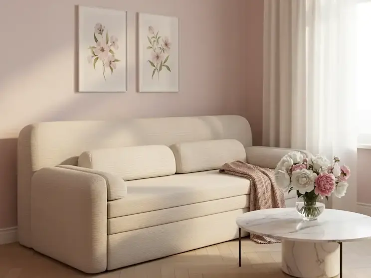 Nowoczesna sofa Elioss Tabbris 18 w jasnej tapicerce w eleganckim salonie z pastelową ścianą, zasłonami i stolikiem kawowym.