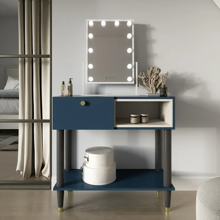 Lustro Flamnaate z podświetleniem LED w formie żarówek ustawione na granatowej toaletce z półką. W tle nowoczesna sypialnia z łóżkiem Meron, zasłonami i delikatnymi dodatkami do pielęgnacji na blacie.