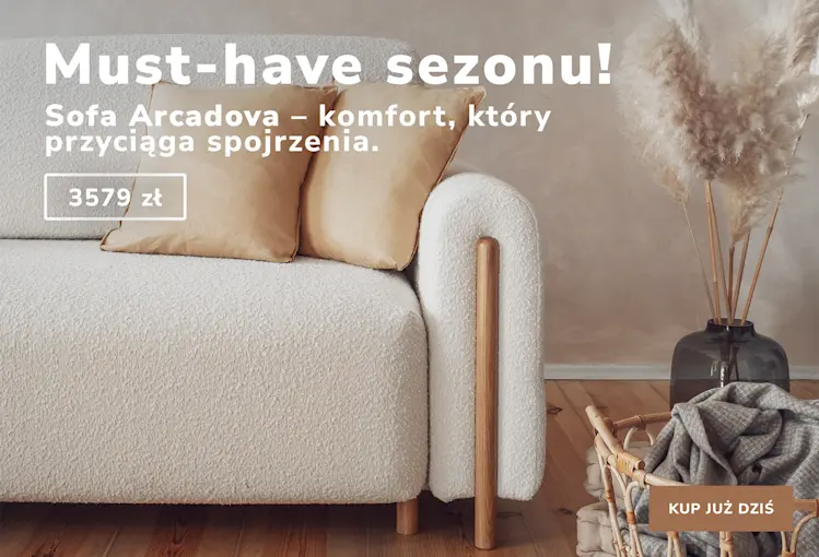 Beżowa sofa Arcadova z jasnymi poduszkami w nowoczesnym wnętrzu z dekoracją z traw pampasowych. Tekst promocyjny: Must-have sezonu! Sofa Arcadova – komfort, który przyciąga spojrzenia. 