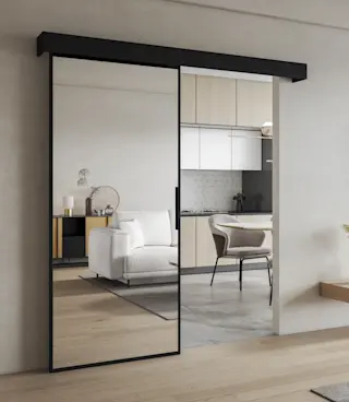 Drzwi przesuwne Lindo z dużą taflą lustra i czarną ramką, w nowoczesnym wnętrzu łączącym salon z kuchnią.