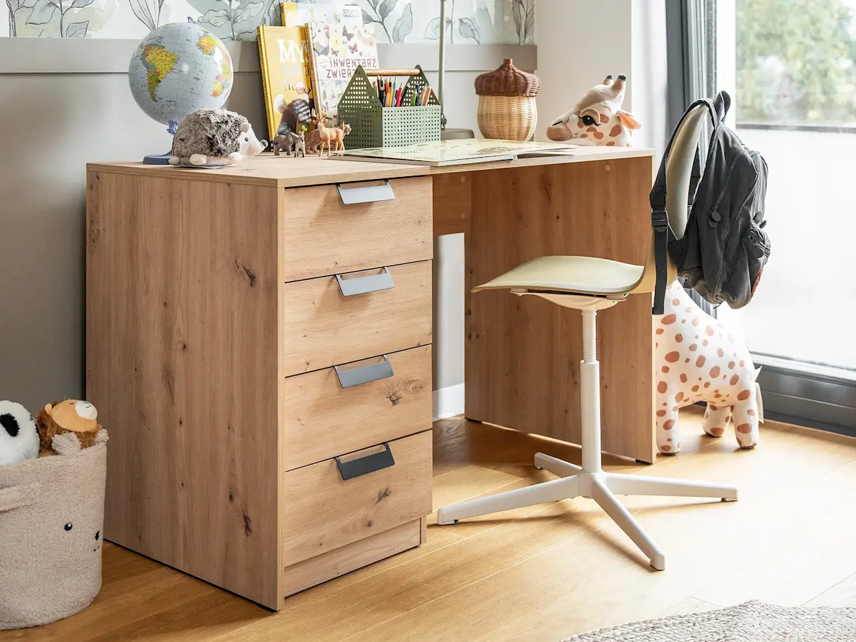 Biurko Barold w dziecięcym wnętrzu, wypełnione książkami, kredkami i zabawkami, tworzące przytulny kącik do nauki przy dużym oknie.