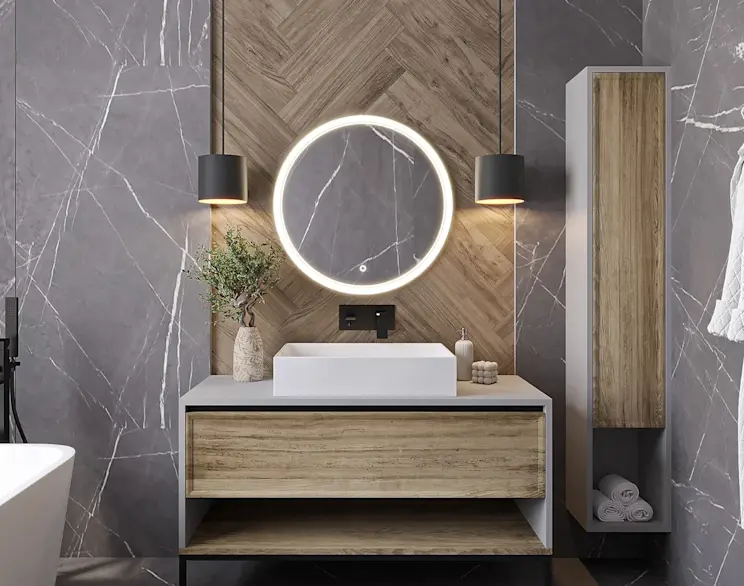 Okrągłe lustro Orandiu LED z podświetleniem zawieszone nad umywalką w nowoczesnej łazience. W aranżacji widać szare płytki z marmurowym rysunkiem, drewniany panel w jodełkę, czarną baterię oraz minimalistyczne lampy wiszące.