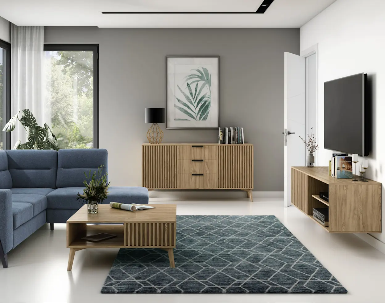 Nowoczesny salon o jasnym wnętrzu. Stoi w nim zestaw mebli inspirowany drewnem z lamelowymi frontami. Po lewej stronie stoi granatowa sofa z jasną poduszką