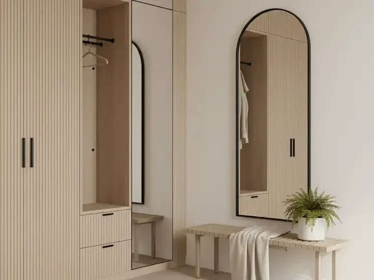 Duże lustro Divva 160x60 cm w czarnej, smukłej ramie zawieszone w jasnym przedpokoju obok zabudowy z lamelami. Owalny kształt lustra optycznie powiększa przestrzeń i dodaje wnętrzu elegancji oraz lekkości.