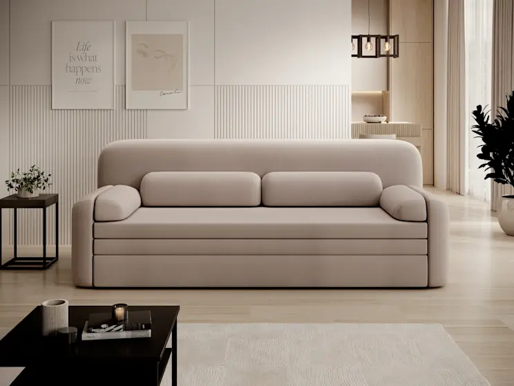 Aranżacja salonu z beżową kanapą Elioss Sola 18 o obłych kształtach i niskiej podstawie. Na pierwszym planie znajduje się czarny stolik kawowy Lanzzi, a w tle widać ścianę z pionowymi frezami oraz lampę wiszącą Giorri