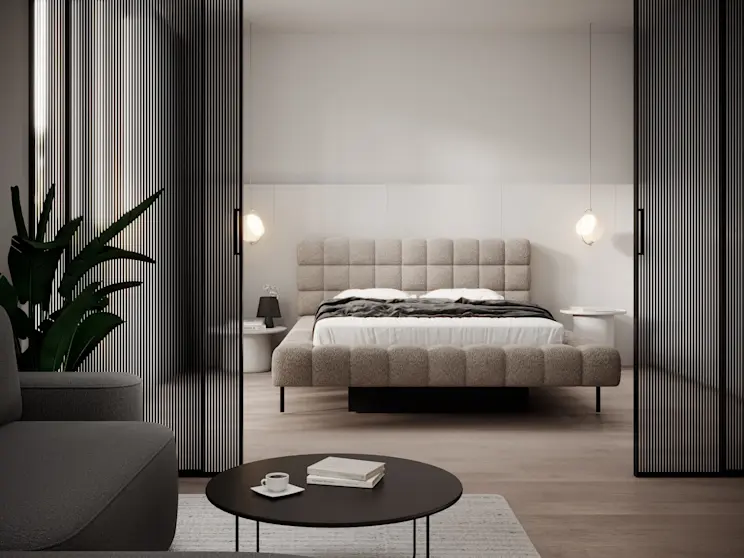 Nowoczesna aranżacja sypialni z łóżkiem Magentta: jasne tapicerowane łóżko na czarnych nóżkach, biała pościel i ciemna narzuta. W tle znajdują się proste ściany, okrągłe stoliki nocne i lampy wiszące.