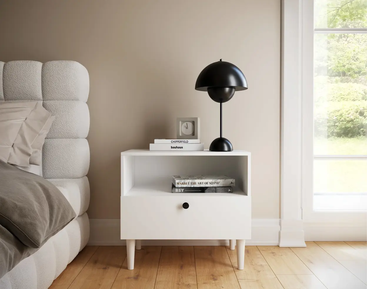 Nowoczesna sypialnia z łóżkiem Dizzle i stolikiem nocnym Dullum, ozdobionym książkami i czarną lampą, utrzymana w ciepłych, stonowanych barwach.