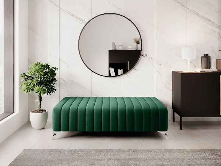 Pufa Laurence jako dodatkowe siedzisko w stylu nowoczesnym – tapicerka w zielonym kolorze i miękka forma pasują do eleganckiego salonu. Obok znajduje się komoda Lanzzi z lampką Vespillo, a duże lustro Divissi i roślina doniczkowa tworzą spójną, harmonijną kompozycję.