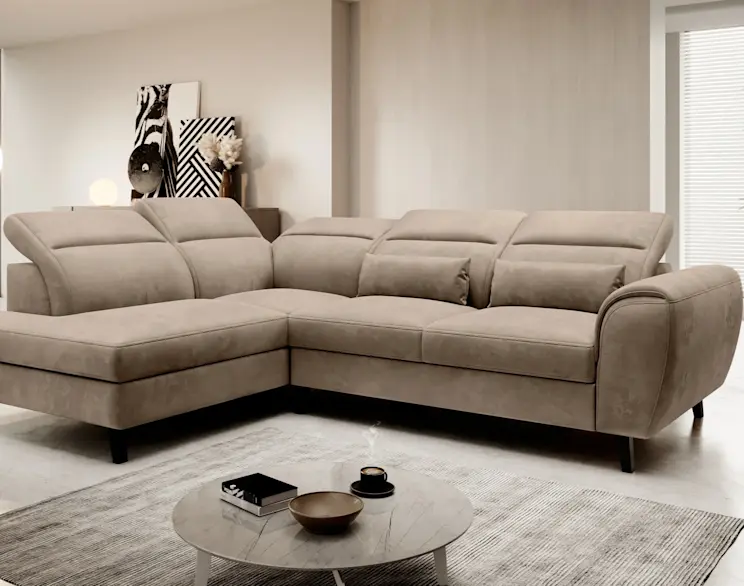 Narożnik Noble Nube 20 w ciepłym, beżowo-brązowym odcieniu mocha mousse ustawiony w nowoczesnym salonie. Widać szeroką szezlongę po lewej stronie, miękkie oparcia i poduszki, a całość stoi na czarnych nóżkach.