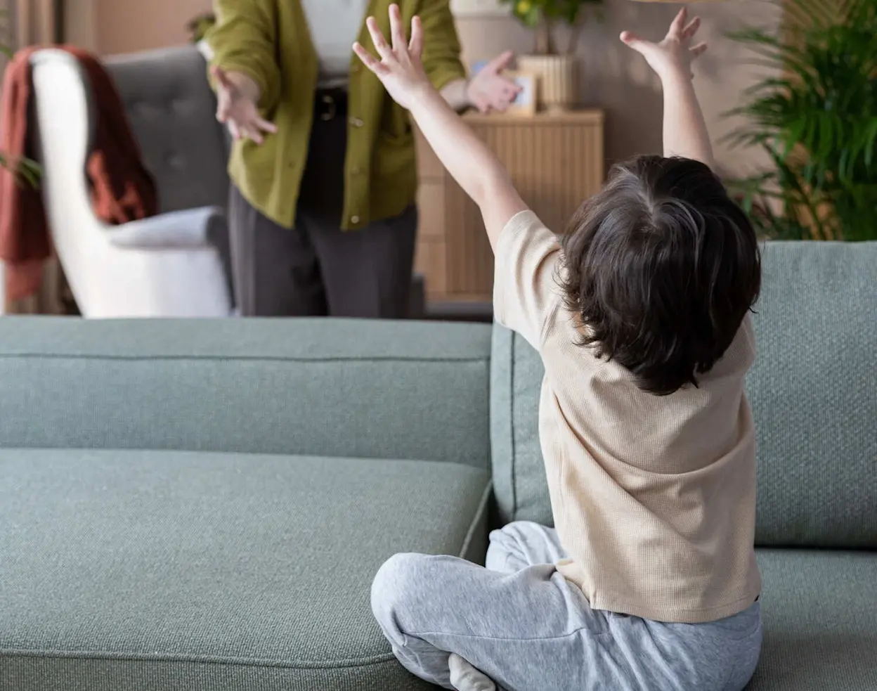 Narożnik Aurumm z funkcją spania w tkaninie Easy Clean, w jasnym salonie. Dziecko siedzi na sofie, a kobieta stoi obok. Praktyczny mebel do rodzinnego domu, odporny na codzienne zabrudzenia.