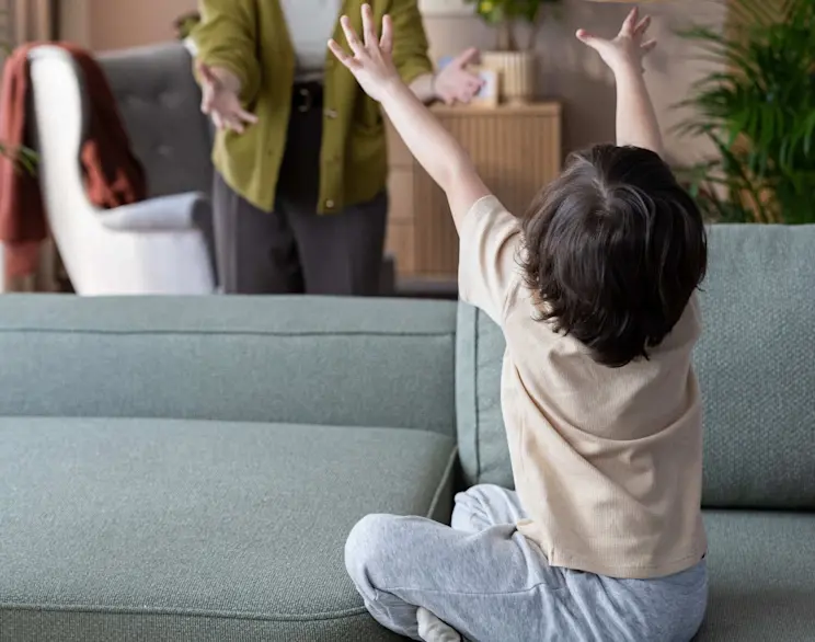 Narożnik Aurumm z funkcją spania w tkaninie Easy Clean, w jasnym salonie. Dziecko siedzi na sofie, a kobieta stoi obok. Praktyczny mebel do rodzinnego domu, odporny na codzienne zabrudzenia.