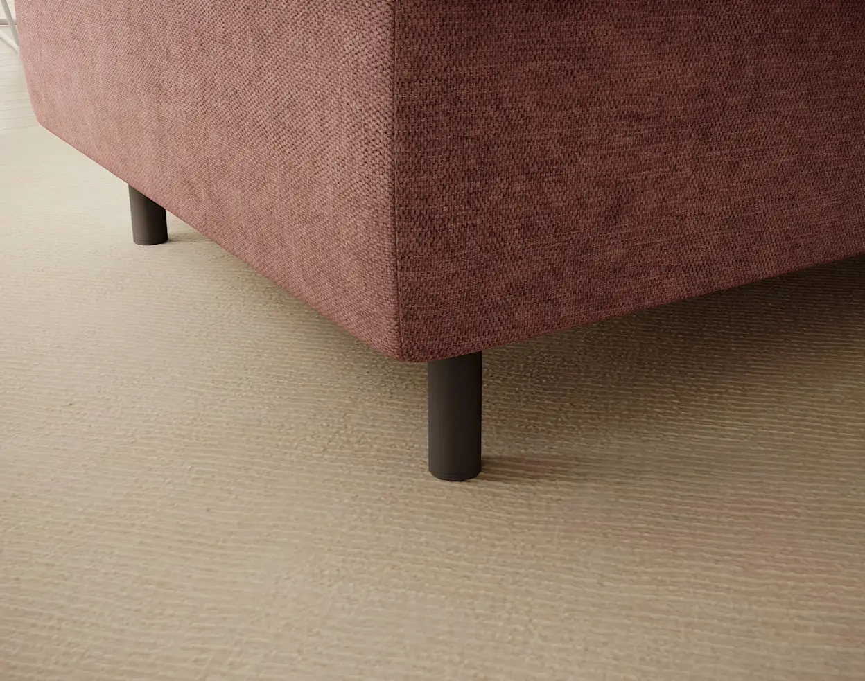 Zbliżenie na pufę Gomsi Raquel 24 w różowej tapicerce: widoczny narożnik mebla, struktura tkaniny oraz czarne, cylindryczne nóżki. Kadr pokazuje staranne wykończenie i stabilną podstawę na jasnej podłodze.
